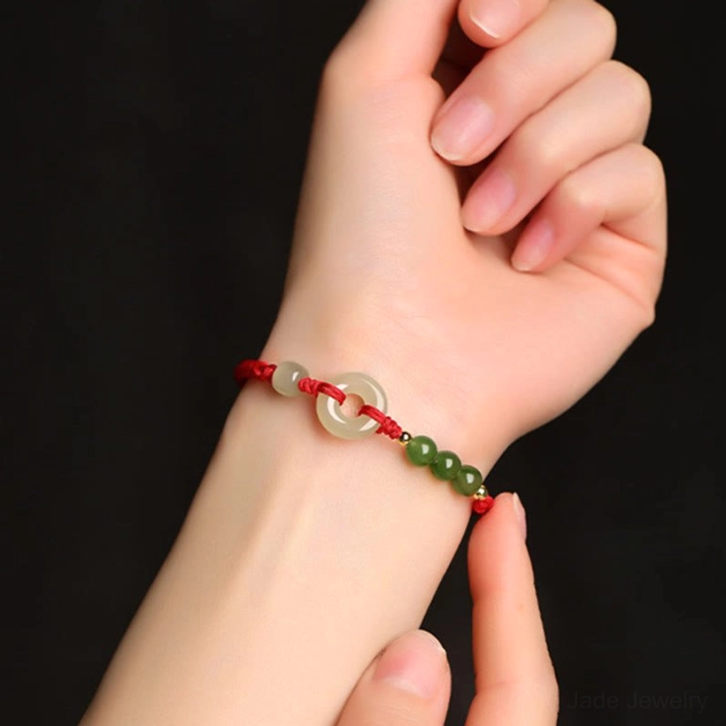 Hetian jade peace buckle bracelet worn on wrist close-up, red rope design against black background