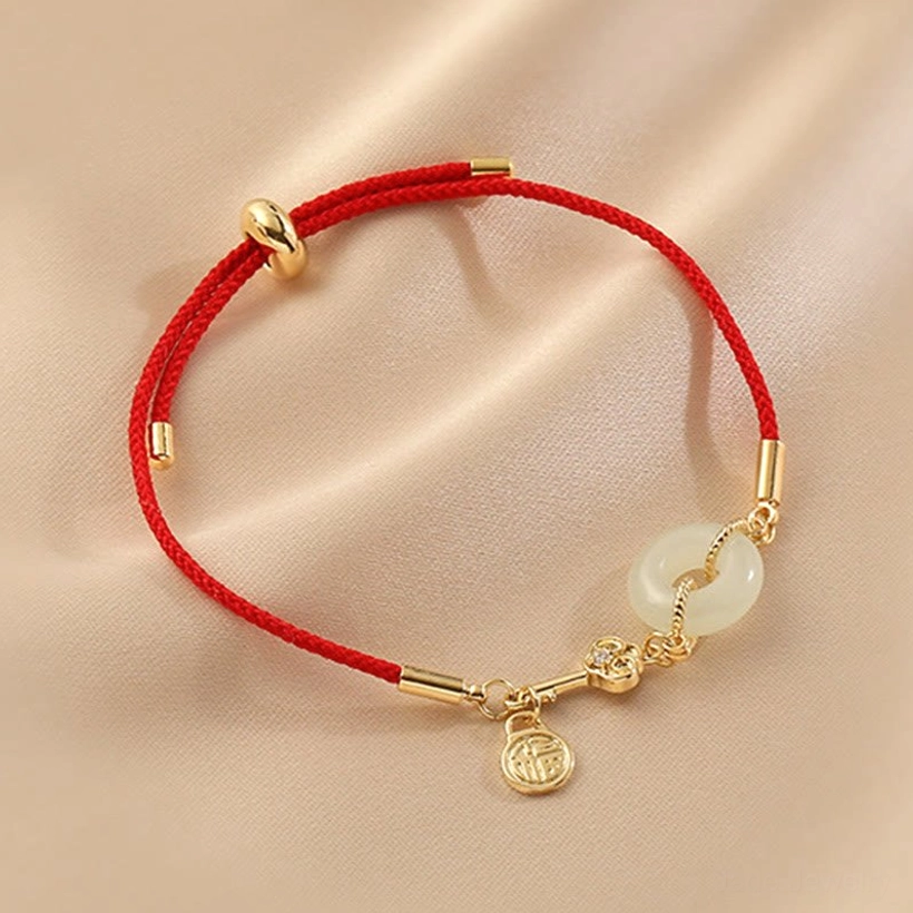 Overhead close-up of white jade donut charm bracelet with gold accents and Fu character pendant on neutral background