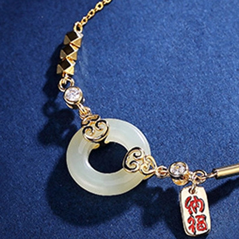 Close-up detail of hetian jade peace buckle with gold scroll decoration and cubic zirconia sparkle accents
