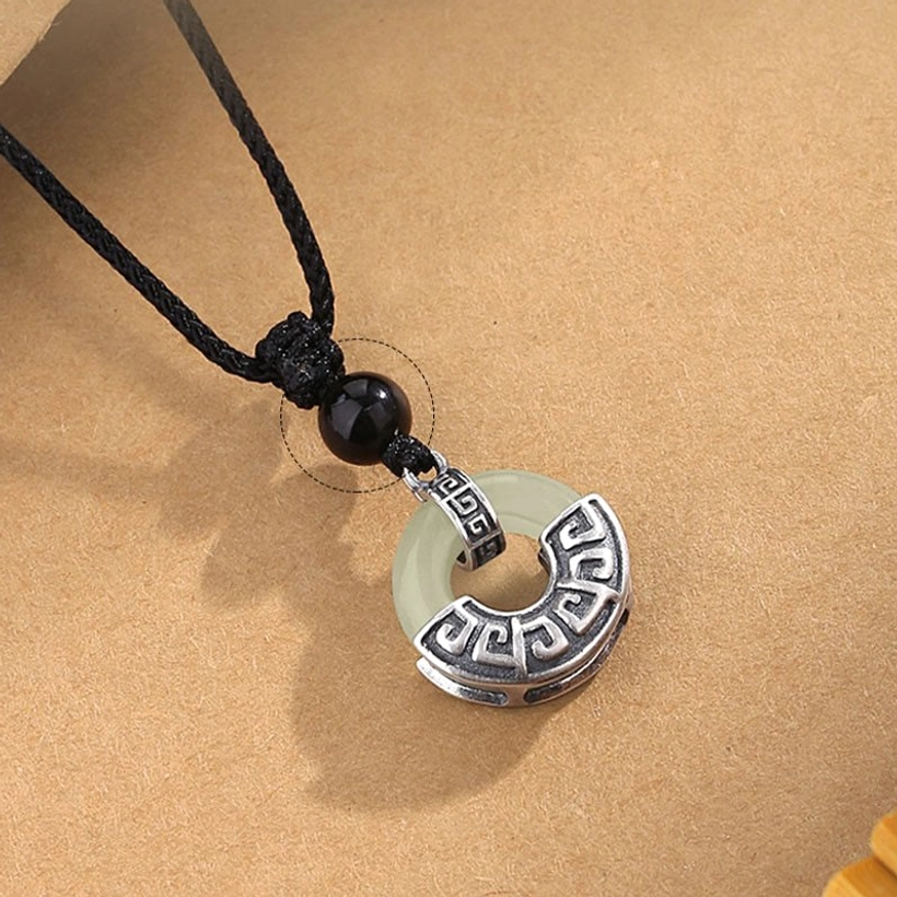 Hetian jade peace buckle necklace detail shot showing black cord knot connection to sterling silver pendant and obsidian bead