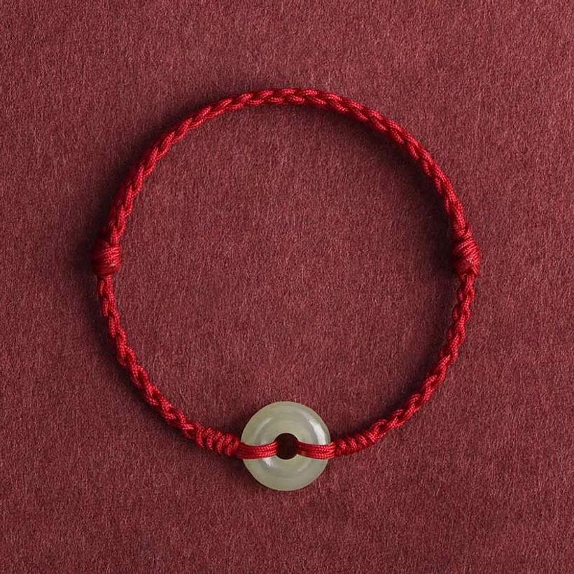 Dark red braided Hetian jade peace buckle bracelet with woven cord on maroon background