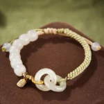 Hetian jade double peace buckle fu character braided bracelet flat lay overhead view on dark velvet mat