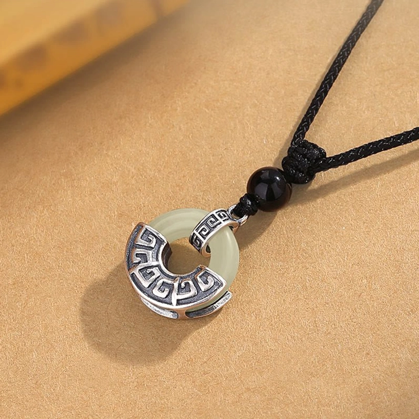 Complete Hetian jade peace buckle pendant necklace full view with black braided cord and silver frame on vintage backdrop