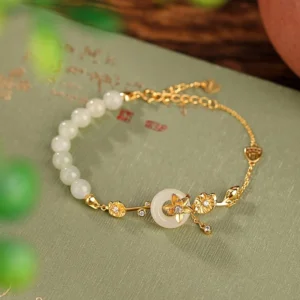 Gold-plated Hetian jade peace buckle lotus bracelet with sterling silver chain on antique calligraphy paper background