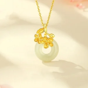 Gold-toned Hetian jade peace buckle necklace pendant with peach blossom design on beige background