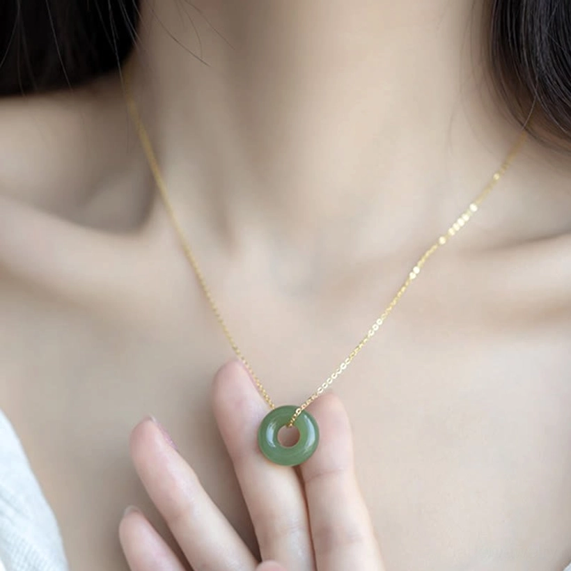 Hetian jade peace buckle necklace close-up showing luminous green jade ring with polished finish and gold connector on light background