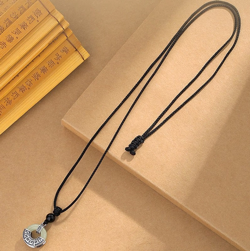 Adjustable Hetian jade peace buckle necklace flat lay showing complete accessory with black braided cord and detachable pendant