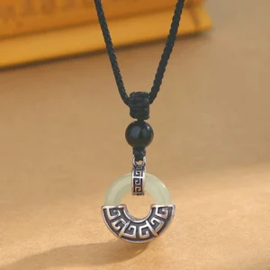 Hetian jade peace buckle pendant necklace with black obsidian bead and sterling silver, front close-up view on light background