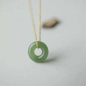 Hetian jade peace buckle pendant front close-up view on light gray background showing smooth green jade ring with polished gold-plated sterling silver chain connector