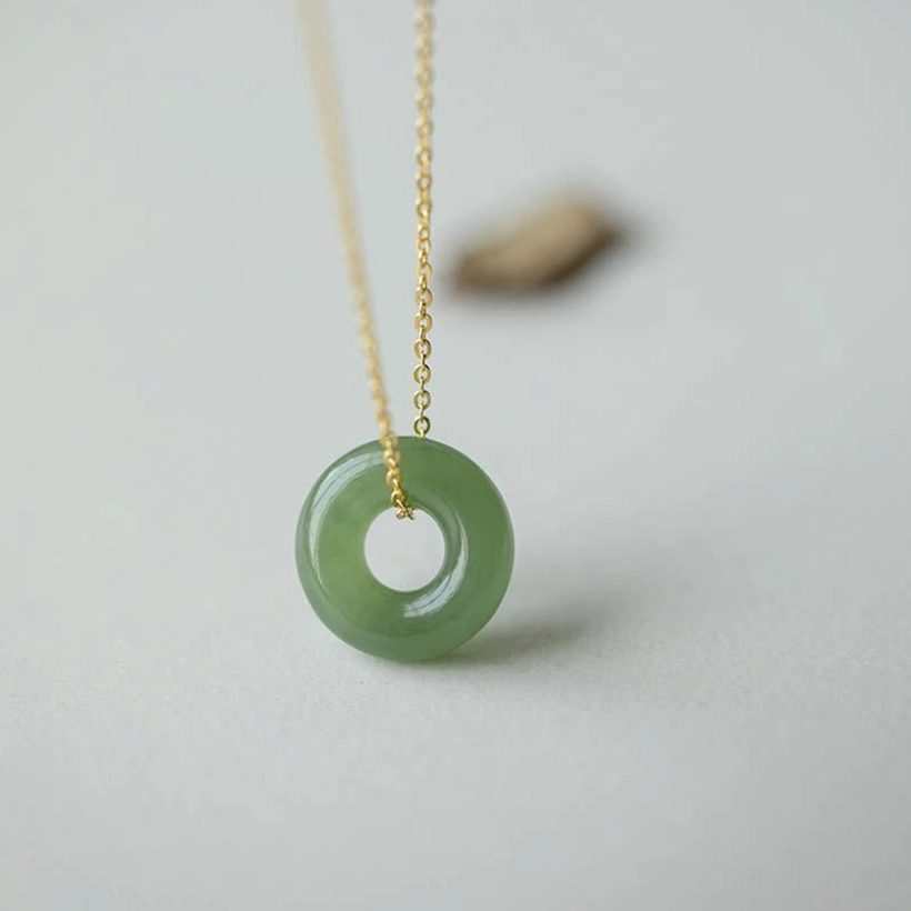 Hetian jade peace buckle pendant front close-up view on light gray background showing smooth green jade ring with polished gold-plated sterling silver chain connector