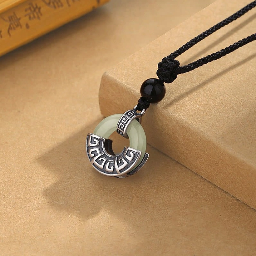 Hetian jade peace buckle silver pendant showing geometric carved details and light green jade hoop, side overhead view