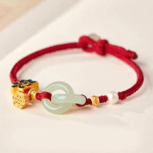 Red braided Hetian jade peace buckle fortune bracelet with gold lotus charm and white pearl flat lay