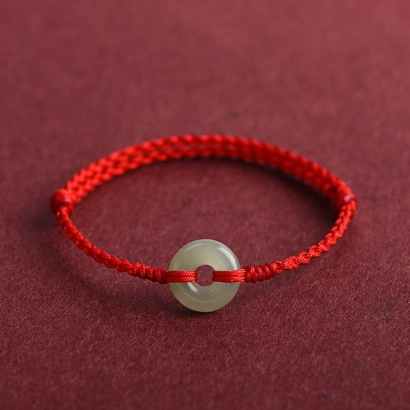 Hetian jade peace buckle attached to red woven braided cord oblique view