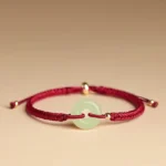 Hetian jade peace buckle bracelet with red braided cord and gold metal beads, top-down side view