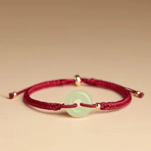 Hetian jade peace buckle bracelet with red braided cord and gold metal beads, top-down side view