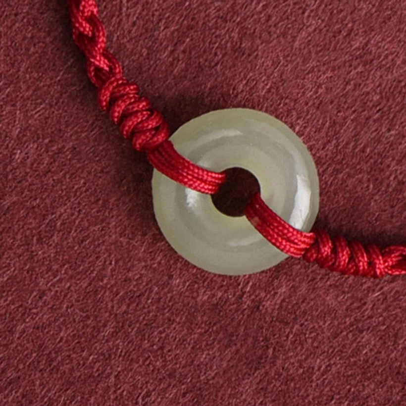 Close-up detailed view of jade peace buckle knot and woven red rope