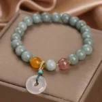 Hetian jade peace buckle bracelet with strawberry quartz on premium satin jewelry box display