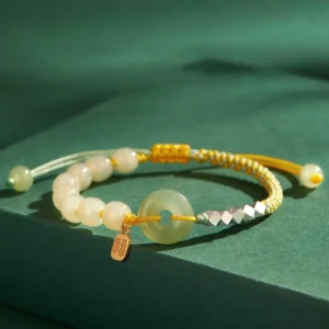 Yellow braided hetian jade peace buckle bracelet with gold charm detail flat lay