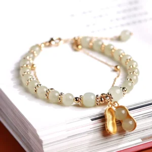 Hetian jade peanut charm bracelet double-layer design pale green jade beads gold spacers close-up view