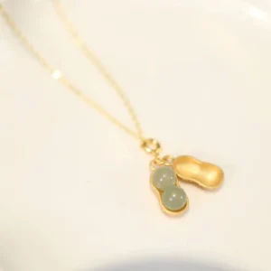 Hetian jade peanut pendant necklace with sterling silver chain, front flat lay view showcasing gold-tone peanut design and light green jade beads