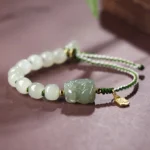 Hetian jade Pixiu bracelet with Fu character pendant - white jade beads and green carved Pixiu on dark desktop