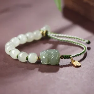 Hetian jade Pixiu bracelet with Fu character pendant - white jade beads and green carved Pixiu on dark desktop
