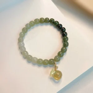 Close-up flat lay of polished hetian jade beads with citrine money bag charm bracelet on light background
