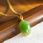 Natural Hetian jade prosperity pendant with 925 sterling silver bezel setting, showcasing smooth polished emerald green jade in classic oval design - side angle view