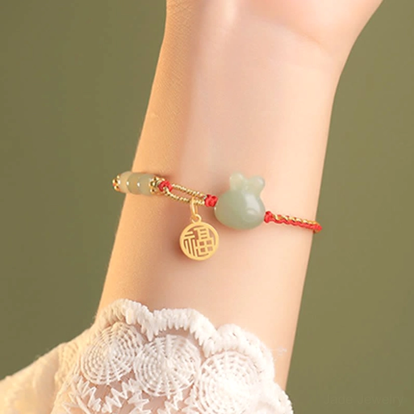 Hetian jade bracelet with thin red rope and jade rabbit charm on model wrist