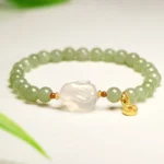 Hetian jade rabbit copper coin prosperity bracelet top view with white agate and gold coin charm on minimalist white background