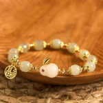 Hetian jade rabbit fu blessing bracelet flat lay top view with gold-plated hardware on wooden tray