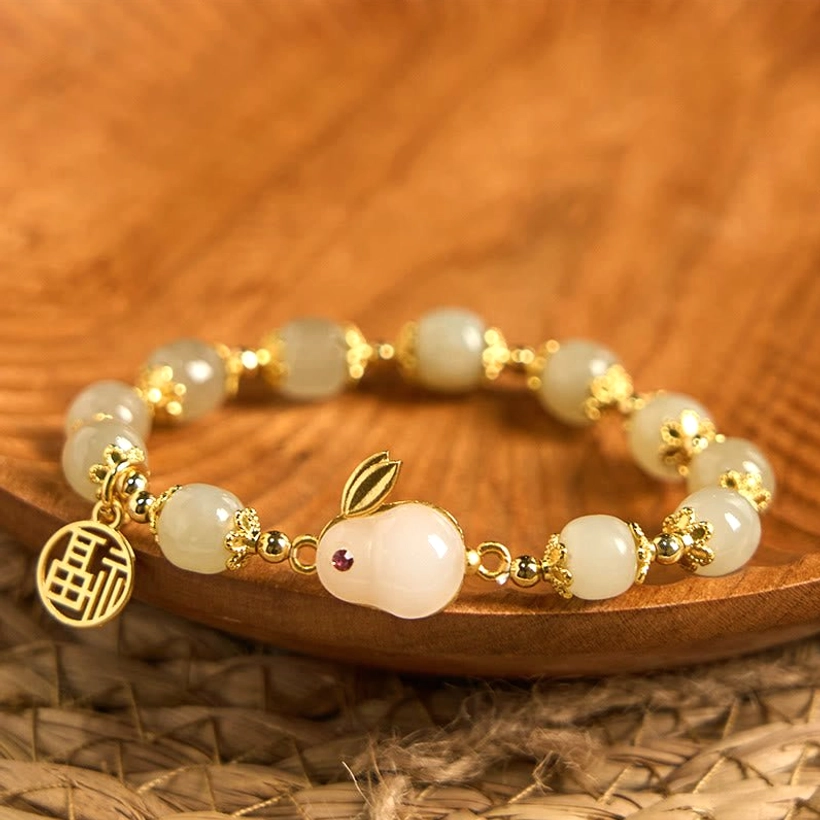 Hetian jade rabbit fu blessing bracelet flat lay top view with gold-plated hardware on wooden tray