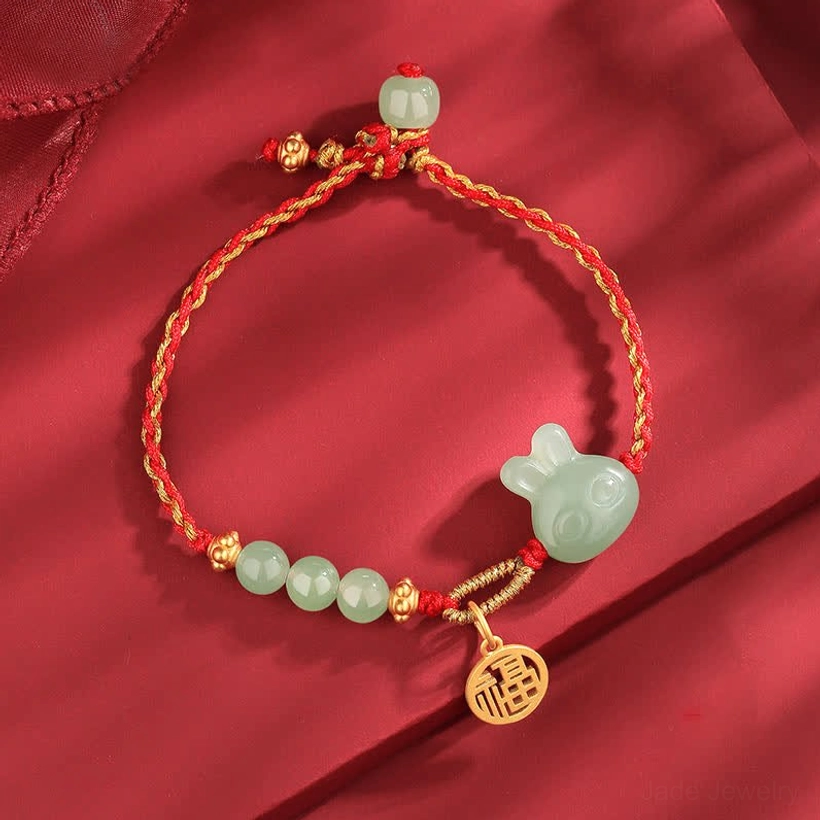 Hetian jade rabbit red string bracelet with 925 sterling silver fu charm on red satin, flat lay top view