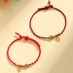 Two Hetian jade red string bracelets with different cord weights and sterling silver charms, flat lay comparison
