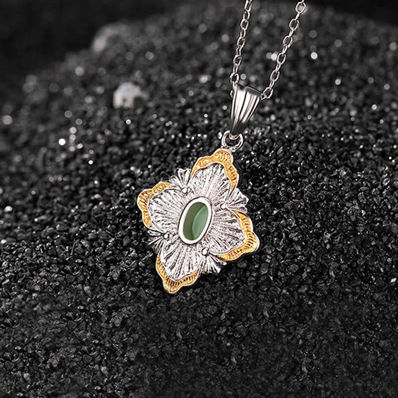 Four-leaf shaped jade pendant with gold-trimmed edges and detailed silver filigree pattern