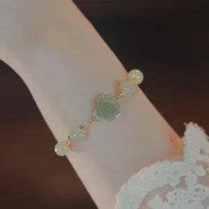 14K gold plated Hetian jade rose flower bracelet worn on wrist with white lace sleeve, showing pale green jade beads and rose charm