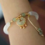 Hetian jade ruyi lock cuff bracelet worn on wrist, showing adjustable band with jade pendant and tassel details