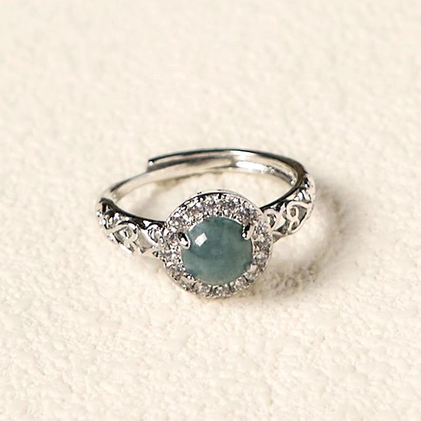 Adjustable hetian jade ruyi ring with floral carved copper band on white background, front view