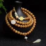 Hetian jade topaz lotus white jade pearl success bracelet with multi-layer beads and gold charm on black display stand
