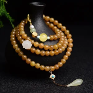 Hetian jade topaz lotus white jade pearl success bracelet with multi-layer beads and gold charm on black display stand