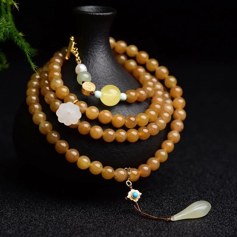 Hetian jade topaz lotus white jade pearl success bracelet with multi-layer beads and gold charm on black display stand