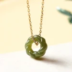 Hand-carved Hetian jade twisted pendant necklace with sterling silver or copper chain, front close-up view showing deep green celadon jade carving