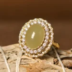 Hetian jade open ring with cubic zirconia halo, front view on natural woven plant background
