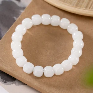 Hetian white jade barrel bead bracelet overhead view on wooden desk, showing uniform smooth polished beads with elastic cord