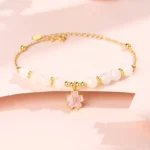 Hetian white jade cherry blossom protection bracelet with 925 sterling silver chain, flat lay view featuring pink enamel sakura pendant and white jade beads on pink studio backdrop