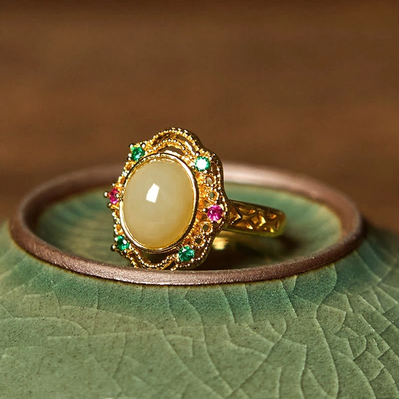 Copper jade ring with floral carved hollow border design, three-quarter front perspective displaying intricate craftsmanship and colored gem details