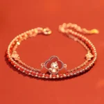 Year of the Horse red agate and hetian jade 925 sterling silver double-layer bracelet with rose gold clover horse charm, red agate beads, and zircon accents displayed on scarlet background