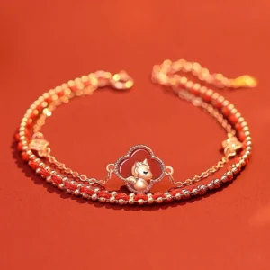 Year of the Horse red agate and hetian jade 925 sterling silver double-layer bracelet with rose gold clover horse charm, red agate beads, and zircon accents displayed on scarlet background