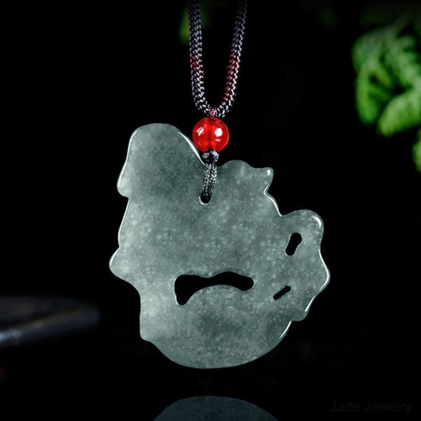 Back view of horse ingot jade pendant showing flat plain jade back with simple hanging loop and red bead on dark cord against dark studio background