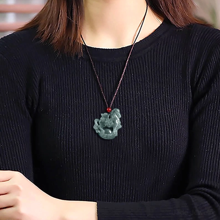 Horse zodiac jade pendant necklace displayed on stand showing natural jade stone with hand-dyed rope cord and red decorative bead in complete display presentation